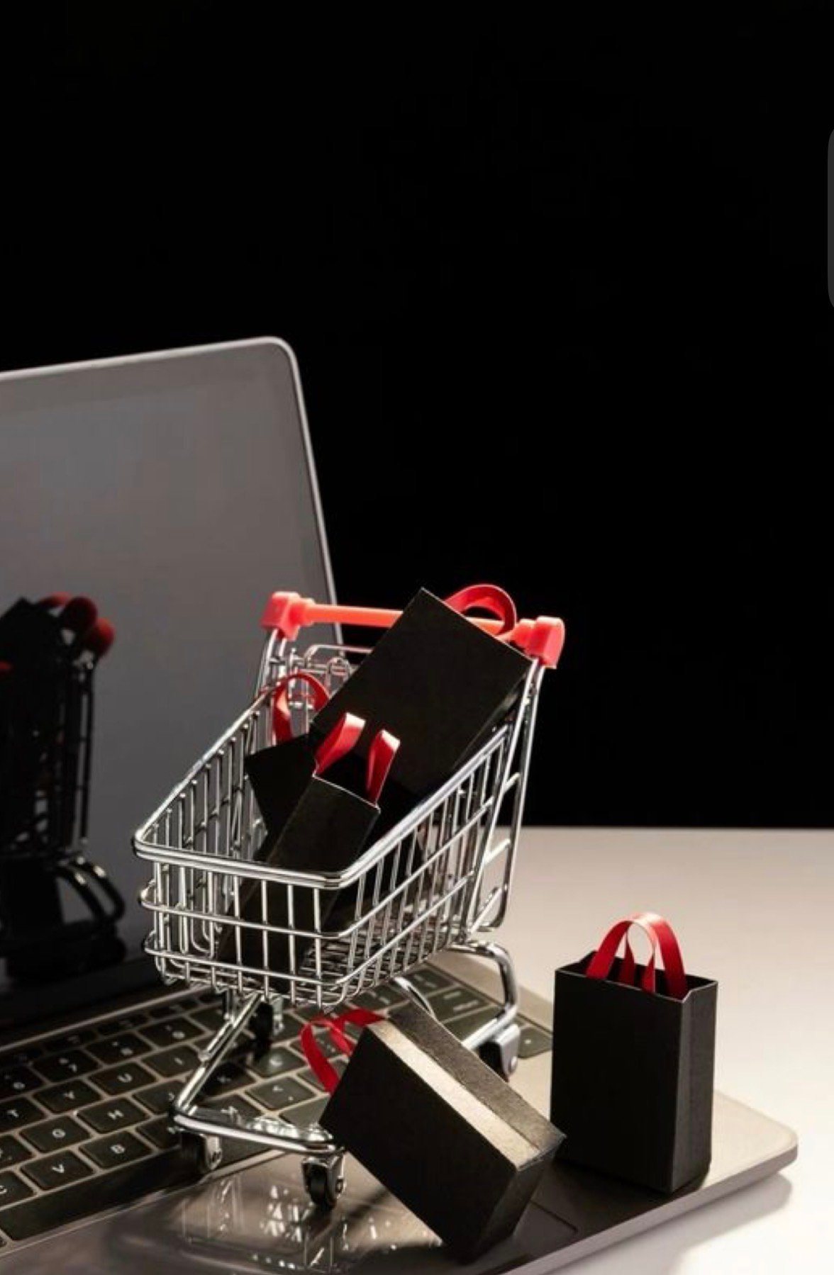 Miniature shopping cart filled with black gift boxes and red ribbons